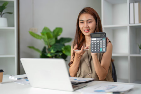 Accounting and Data Analysis. A woman using a calculator in a virtual meeting, showcasing her analytical skills.の写真素材