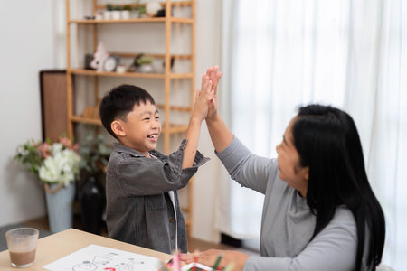 Back to School and Celebration. A joyful moment between a mother and son as they share high-fives during school preparations.の写真素材