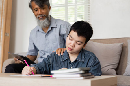 Guidance and Support in Learning. A grandfather provides assistance as his grandson focuses on his studies.の写真素材