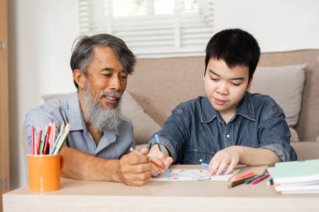 Creative Learning and Family Bonding. A grandfather helps his grandson with art activities, fostering creativity and connection.の写真素材