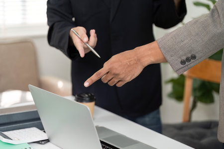 Pointing and Discussion. Two professionals pointing at a laptop screen during a meeting.の写真素材