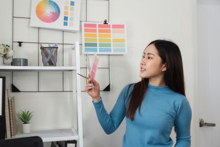Color Analysis and Design Development. A designer showcasing a vibrant palette while checking design elements in a professional environment.の写真素材