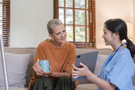 Young Nurse Offering Health Care Advice to Elderly Woman in a Cozy Home Setting, Promoting Wellness and Supportive Care for Seniorsの写真素材