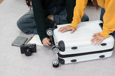 Wellness and teamwork: Women fixing luggage wheels and planning travelの写真素材