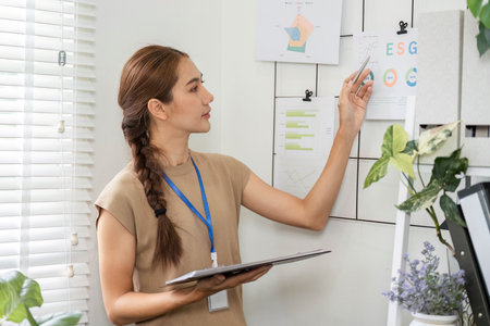 ESG sustainability management with woman reviewing metrics on wall