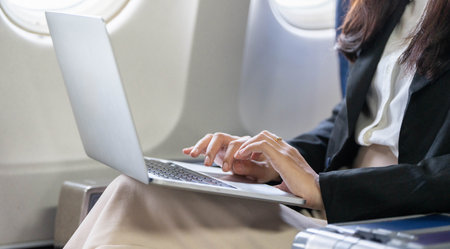 Business travel: Close-up of young woman typing on a laptop in-flight