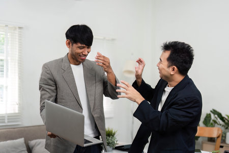 Business Strategy and Team Spirit. Two men celebrating a successful collaboration, reflecting teamwork and positive energy in a modern office.の写真素材