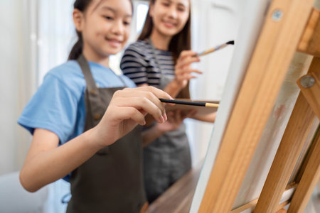 Family time sharing creativity: Mother and daughter painting togetherの写真素材