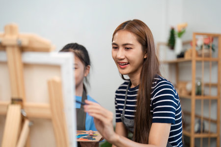Family time with a mother teaching painting techniques to her childの写真素材