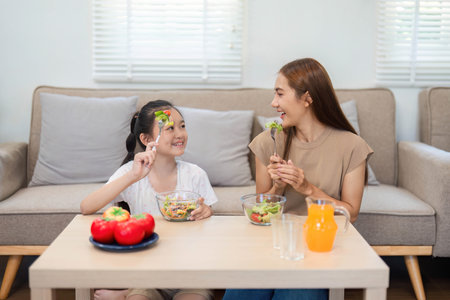 Wellness through healthy eating: Mother and daughter enjoying saladsの写真素材