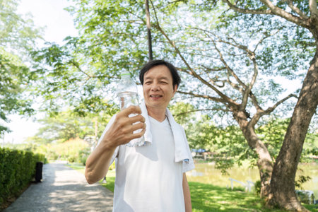 Wellness and Joy. Man smiling while holding a water bottle during a morning walk in nature.