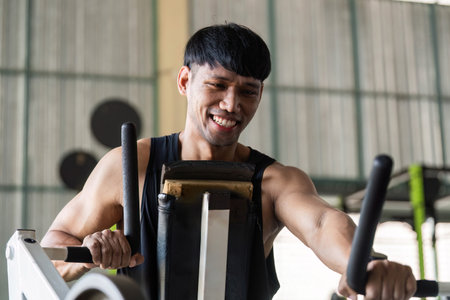 Fitness Motivation. Young man smiling while using gym equipment.の写真素材
