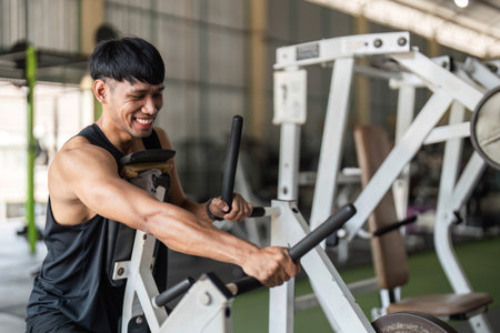 Fitness Enthusiasm. Young man using gym equipment for strength training and muscle growth.の写真素材