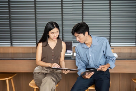 Business Collaboration and Insight Sharing. Young professionals discussing projects in a stylish office.の写真素材