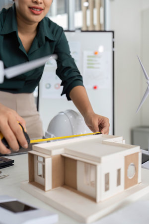 Precision in Architectural Design. Close-up of architect measuring building model for accuracy.