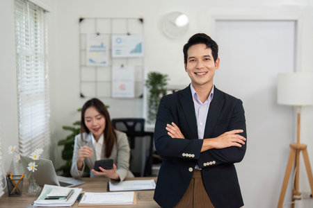 Professional Confidence and Collaboration. A smiling businessman standing proudly in a modern office.の写真素材