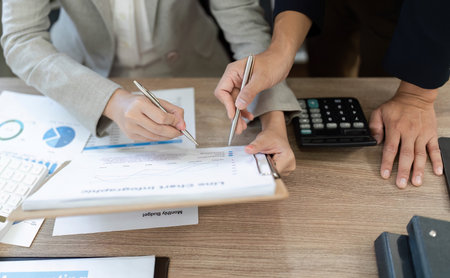 Detailed Financial Review. Professionals analyzing financial documents and discussing strategies in an office.の写真素材