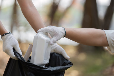 Teamwork in action: volunteers disposing of waste during a park cleanupの写真素材