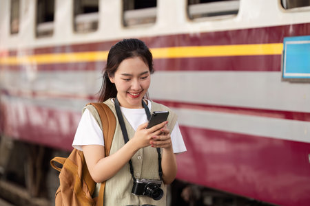 Adventure and Excitement. A smiling traveler immersed in her smartphone at the train station.