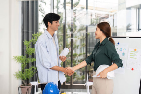 Professional Handshake in Sustainable Engineering. Young engineers finalizing ESG project plans in office.の写真素材