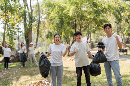 Group of enthusiastic volunteers proudly posing after a successful park cleanup, promoting environmental awareness.の写真素材