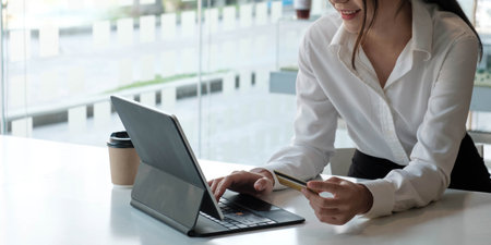 Young Asian businesswoman enjoy shopping online using credit card at a coffee shop.