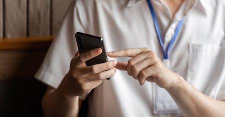 Close-up of young professional using smartphone to communicate while working in modern office.