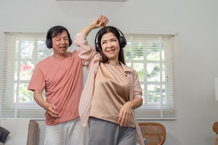 Older couple enjoying a dance together with headphones at home.の写真素材