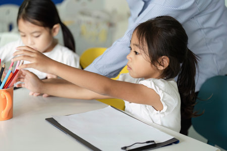 Back to School. Children reaching for colorful pencils in a classroom.の写真素材