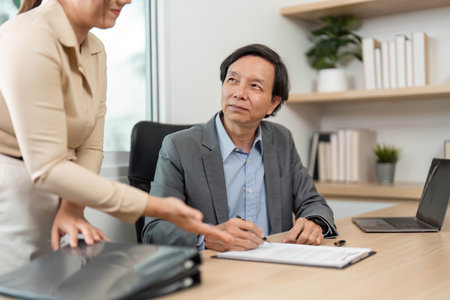 Professional Discussion and Document Review. Businessman signing paperwork during a meeting with a colleague.の写真素材