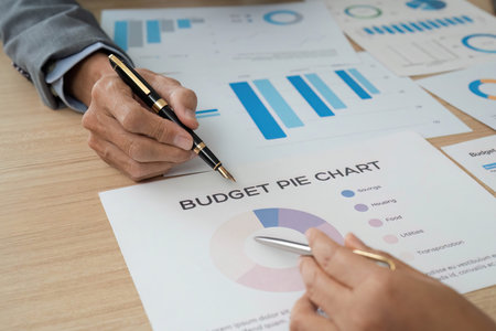 Budget Planning and Financial Analysis. Close-up of hands reviewing budget pie chart and financial graphs.の写真素材