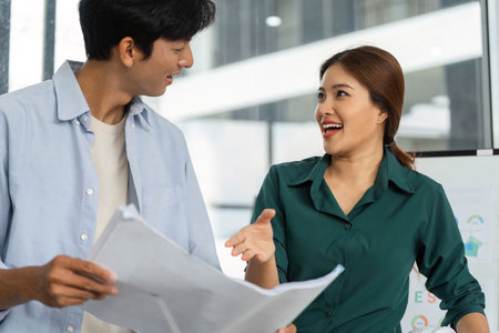 ESG and Sustainability. Two professionals discussing eco-friendly building plans in a modern office.の写真素材