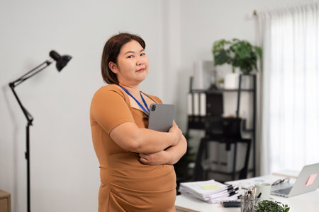 Confident Business Woman Holding Tablet in Modern Office Setting with Professional Attire and Positive Expressionの写真素材