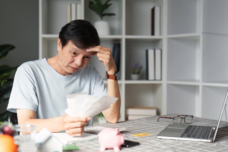 Concerned man reviewing bills and managing finances at his desk with a piggy bank
