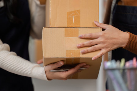 Women exchanging packaged merchandise during an online delivery at a modern workspace
