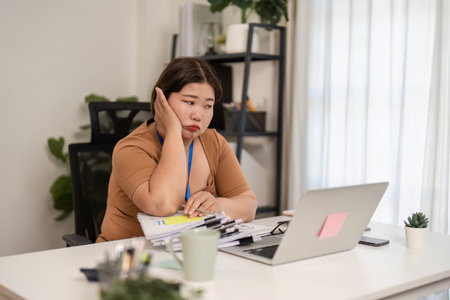 Overwhelmed female accountant struggling with multiple documents in a challenging office environmentの写真素材