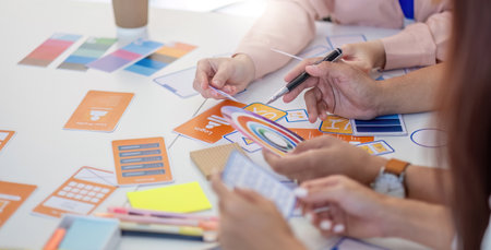 Team of Designers Collaborating. Professionals discussing layout concepts and color selections at a creative workspace.の写真素材
