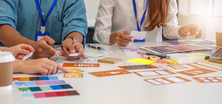 Design Professionals Collaborating on Concepts. Team discussing layout designs and color choices in...