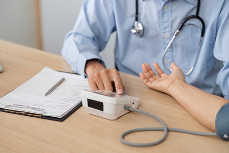 Doctor Conducting Health Assessment with Device. Physician using a blood pressure monitor during a checkup.の写真素材