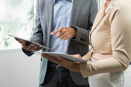 Collaboration in Business. Two professionals discussing data on digital tablets in office.の写真素材