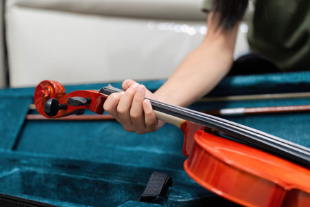 Music Instruments and Learning. A close-up of a childs hand holding a violin in a case.