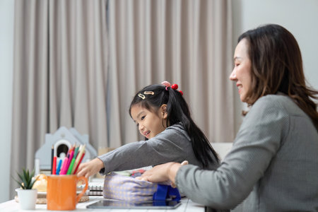 Preparation for School. Girl excitedly packing her bag with mothers help.の写真素材