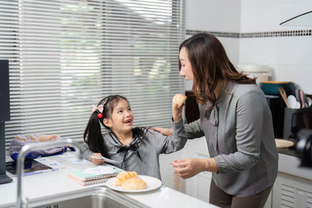 Happy Moments. A mother and daughter share a delightful snack in the kitchen.の写真素材