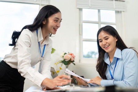 Teamwork in Action. Two businesswomen discussing financial documents at office table.の写真素材