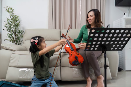 Musical Bonding. Mother and daughter sharing a moment with a violin during practice.の写真素材