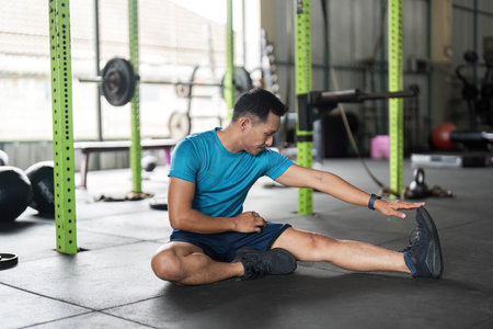 Fitness Stretching Routine. Male athlete reaching for his foot during a gym workout.