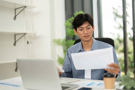 Remote Work and Professionalism. Young businessman reviewing documents while working from home.の写真素材