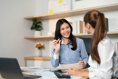 Professional Women Engaged in Discussion. Two colleagues collaborating on financial strategies.の写真素材