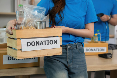Donation and Generosity. Volunteer holding a donation box filled with essential items.の写真素材