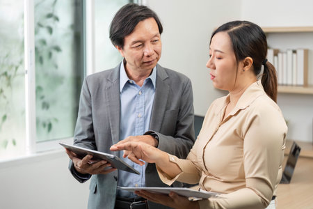 Professional Discussion. Business partners reviewing data on tablets in modern office.の写真素材